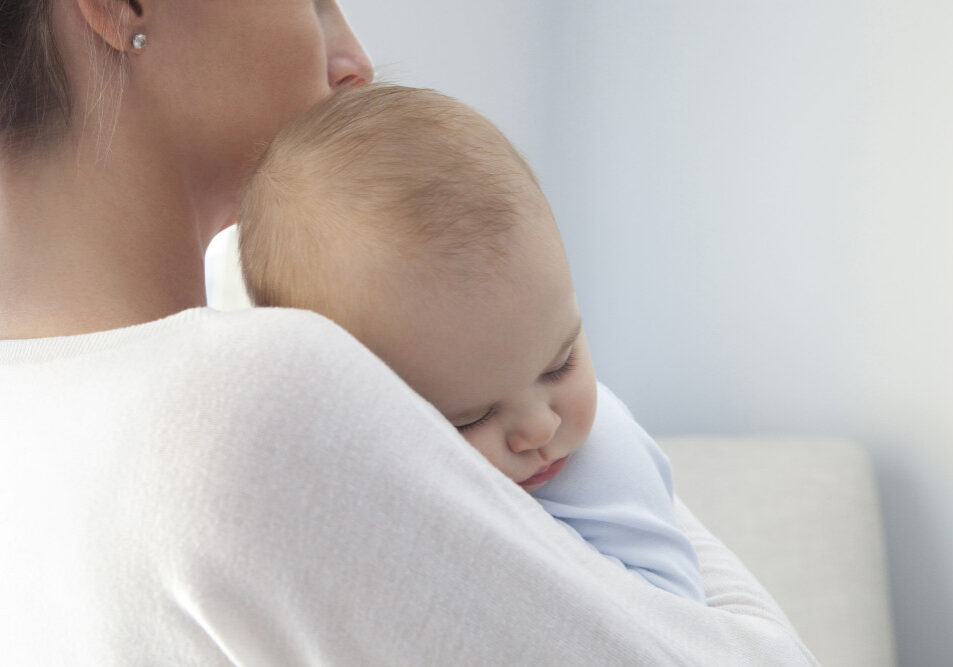 Close up of a mother with her eight months old baby boy sleeping in her arms. Photographed with a Canon 5D Mark II and developed from raw file.